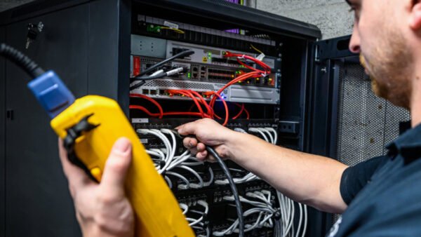 Een man is bezig met een server en heeft een geel apparaat in zijn hand