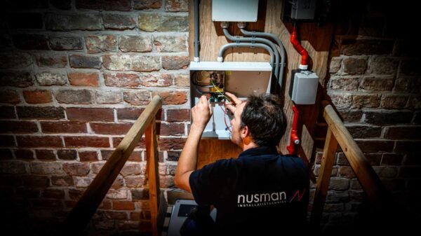 Een man is bezig met het repareren van een brandinstallatie tegen een stenen muur