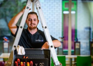 Een man houdt een ladder vast met gereedschap voor de ladder