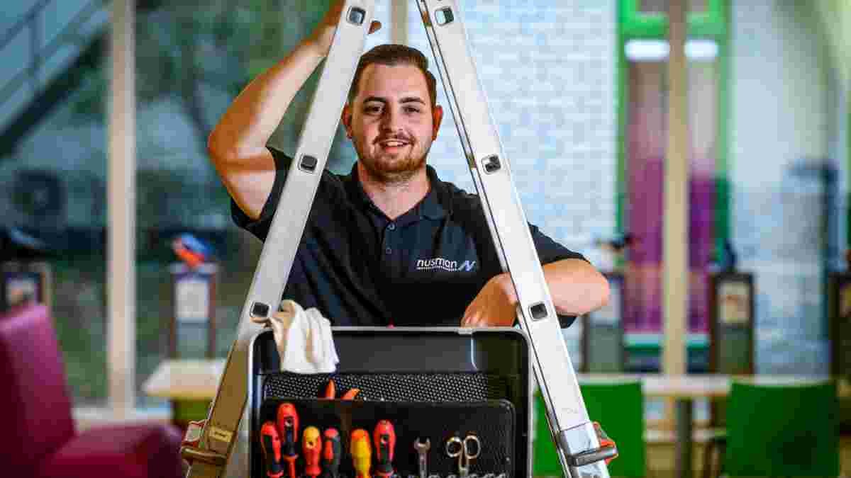 Nusman monteur geposeerd met ladder en gereedschapskoffer