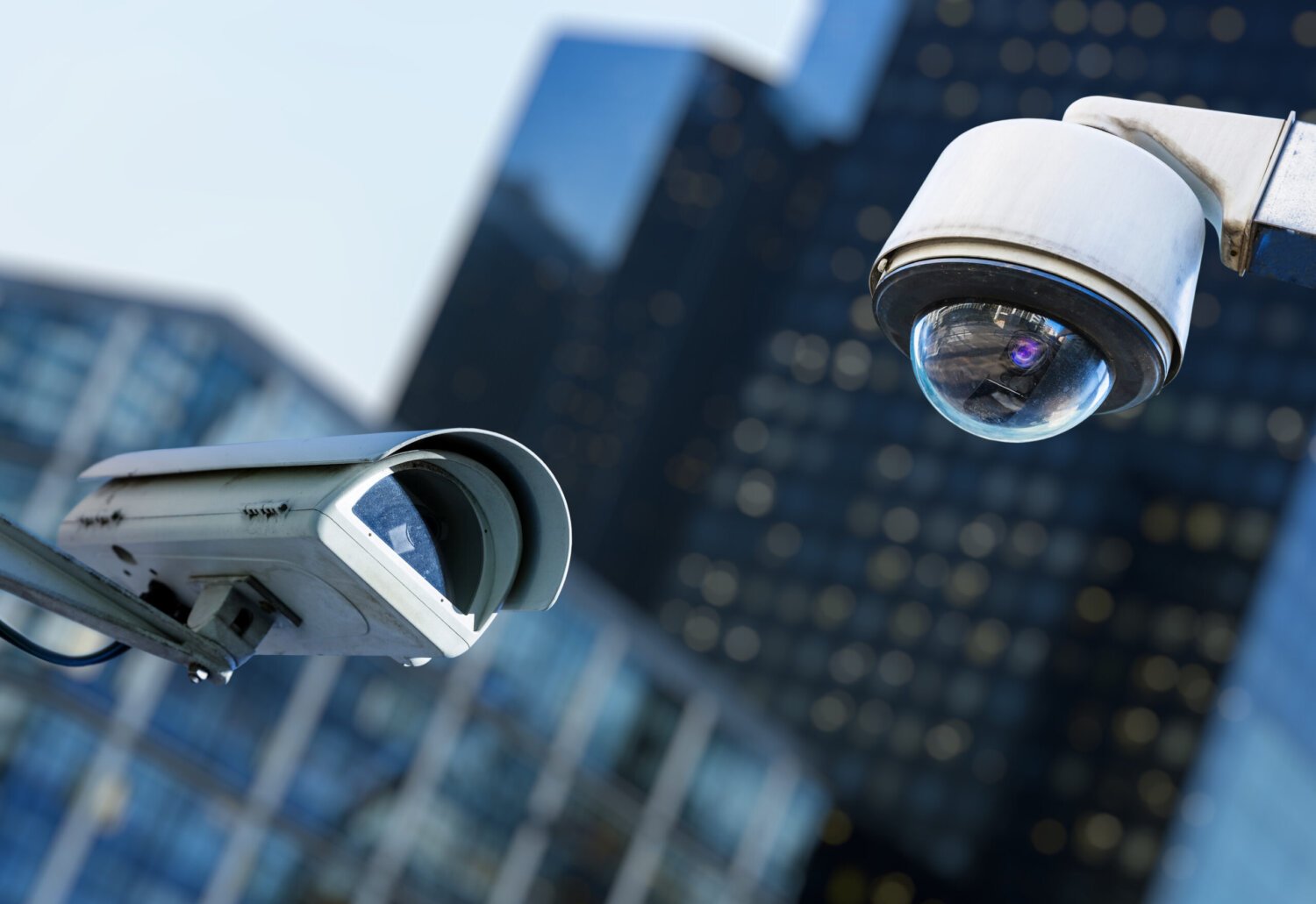 Twee veiligheidscamera van kabeltelevisie in een stad met wazig bedrijfsgebouw op achtergrond
