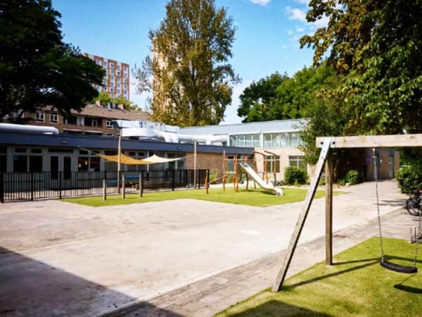 Het vernieuwde schoolgebouw en schoolplein aan de Bessemoerstraat in Groningen met speeltoestellen en schaduwdoeken