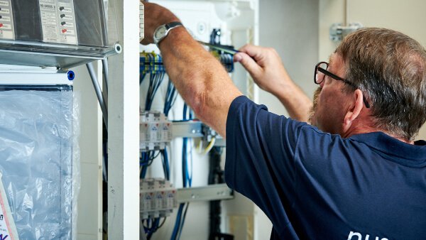 Monteur van Nusman Installatietechniek voert elektrotechnische werkzaamheden uit aan een verdeelinrichting in Groningen en regio Noord.