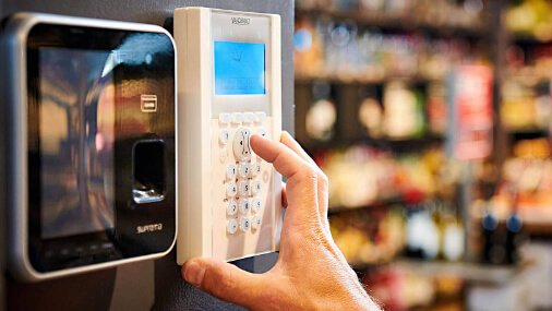 Medewerker van Nusman Installatietechniek Groningen die een brandmeldsysteem bedient via een codepaneel en biometrische toegangscontrole.