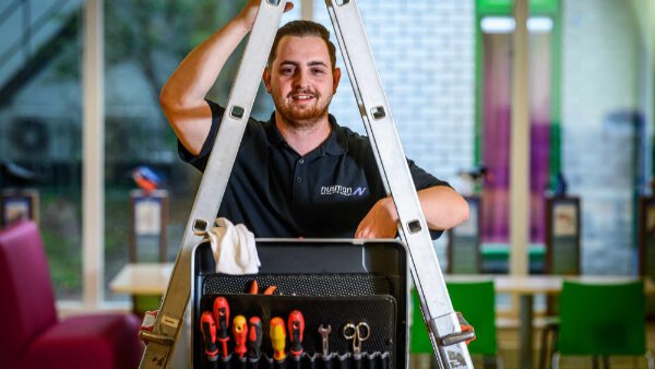 Monteur van Nusman Installatietechniek met gereedschap op een ladder, klaar voor installatie- en onderhoudswerkzaamheden in Groningen.