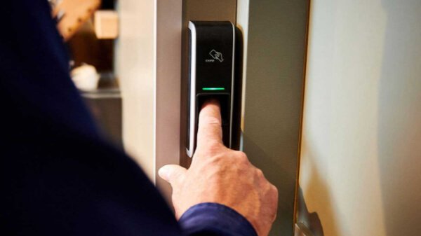 Medewerker van Nusman Installatietechniek Groningen die een biometrische toegangslezer gebruikt als onderdeel van een brandmeld- en beveiligingssysteem.