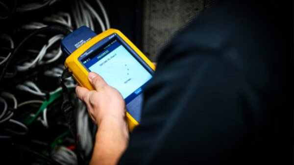 Monteur voert een netwerk- en datakabelmeting uit met een Fluke Networks tester tijdens periodiek beheer en onderhoud.