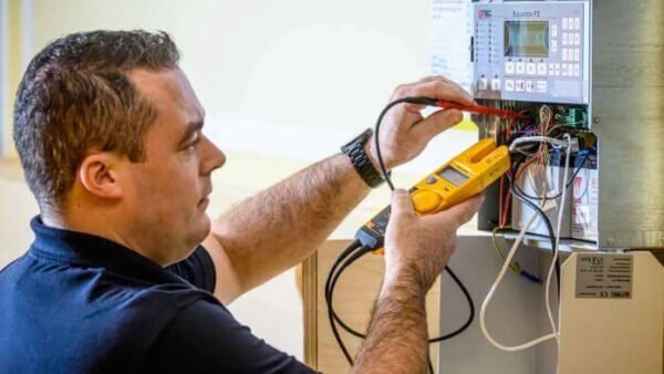Inspecteur van Nusman Installatietechniek voert een Scope 8 meting en controle uit op een NSC Solution F2 brandmeldcentrale met een multimeter.
