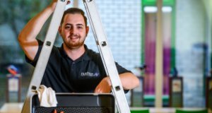 Een man houdt een ladder vast met gereedschap voor de ladder